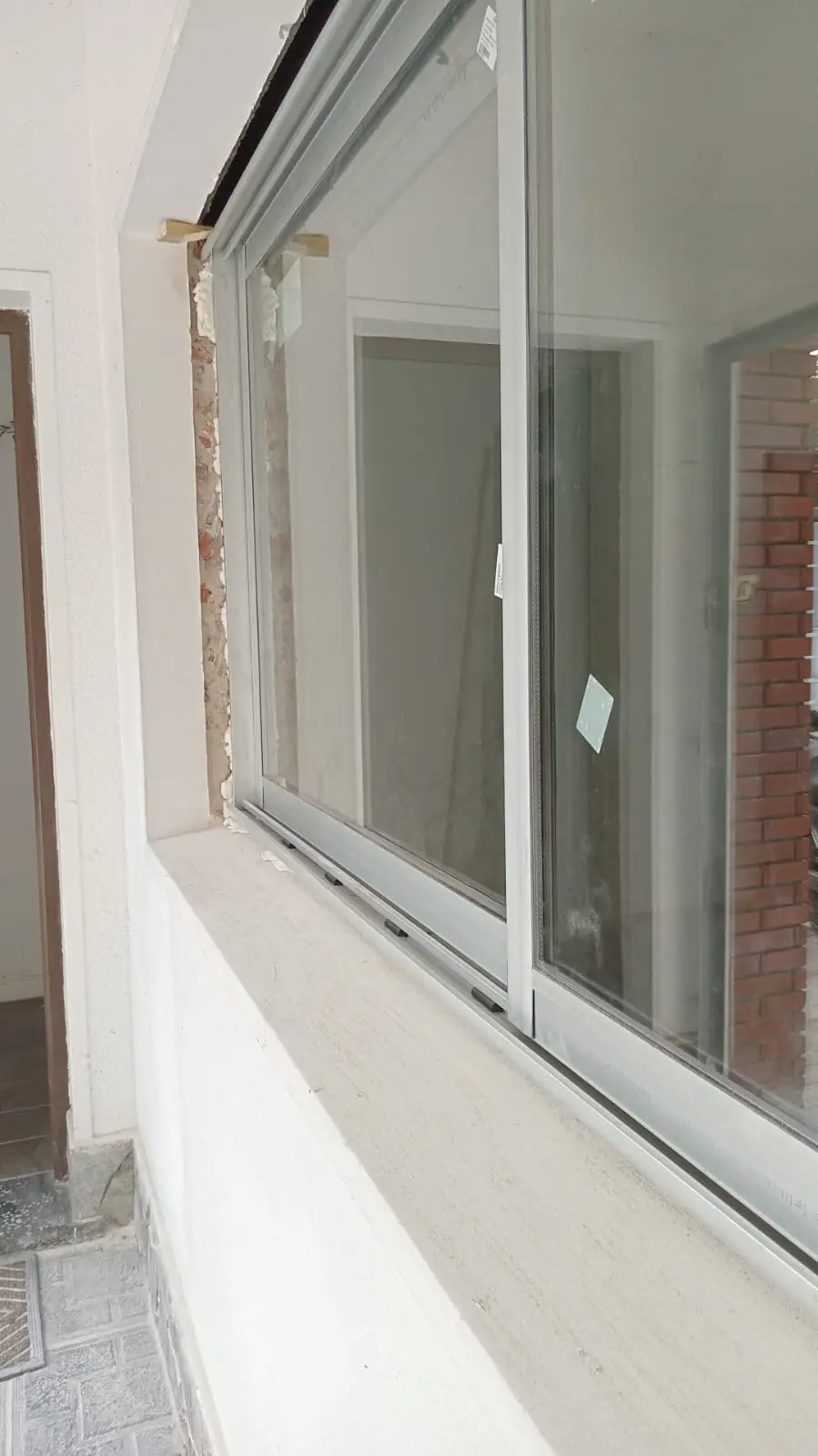 Ventana corrediza de aluminio blanco recién colocada en una pared en obra