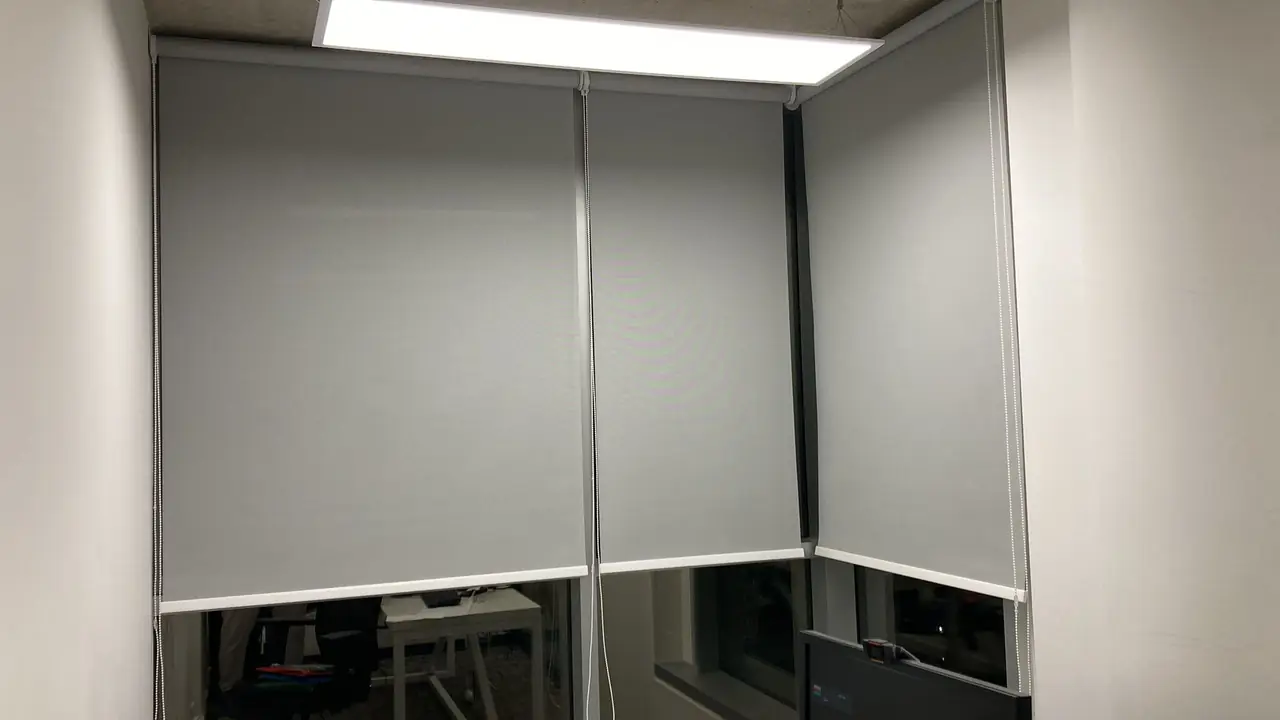Cortinas roller grises instaladas en los ventanales de una oficina