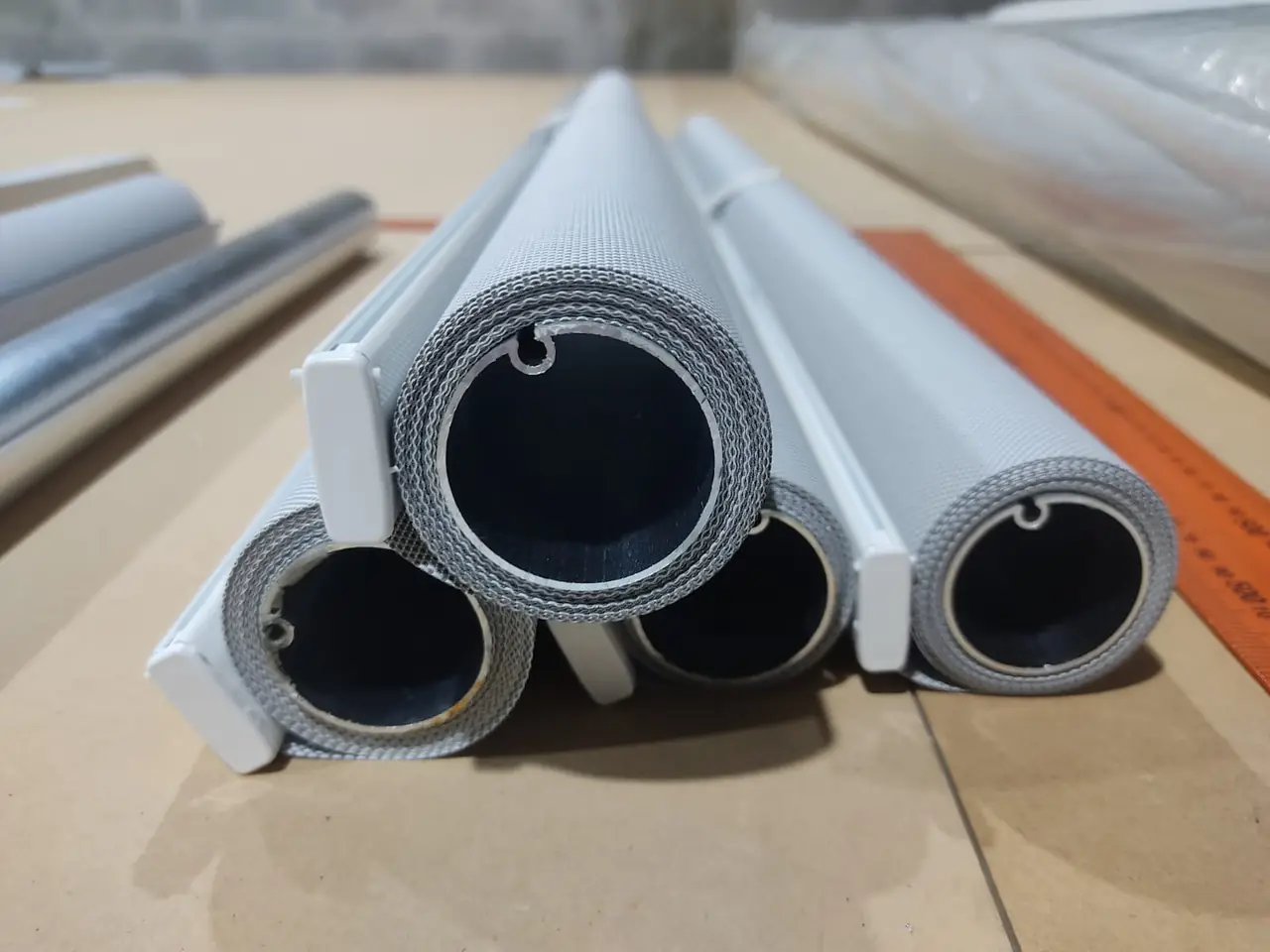 Tubos de cortinas roller con la tela enrollada, vistos de frente en el taller