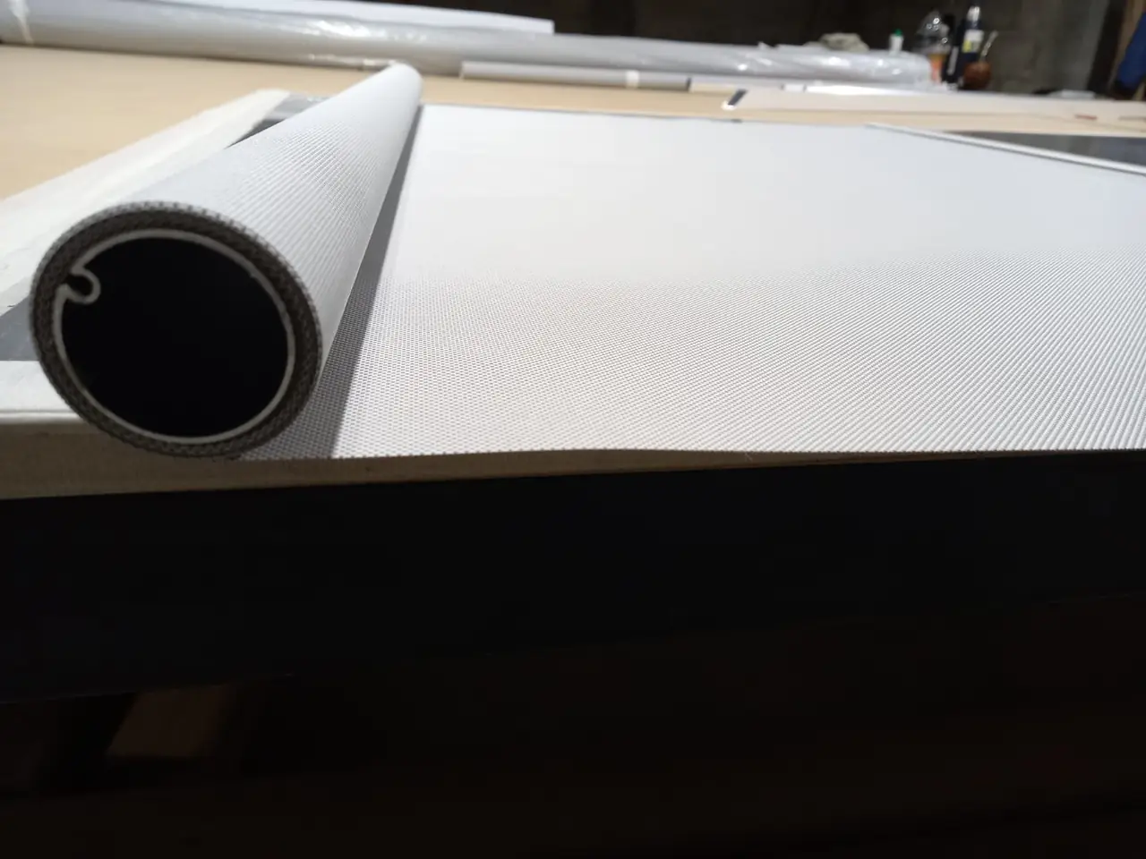 Tela de una cortina roller enrollada en su tubo sobre la mesa de trabajo