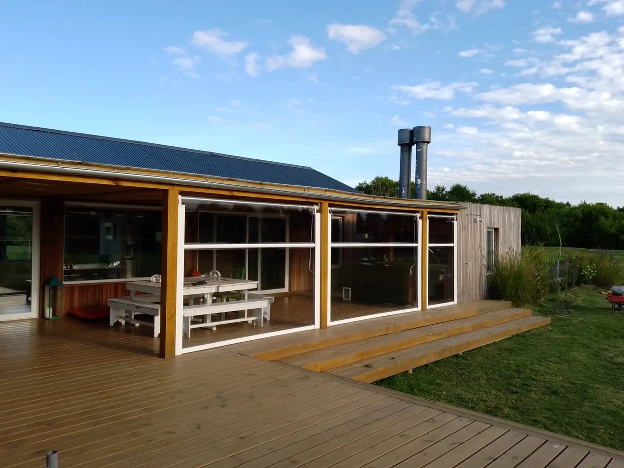 Galería con cerramientos de PVC transparente sobre un deck de madera