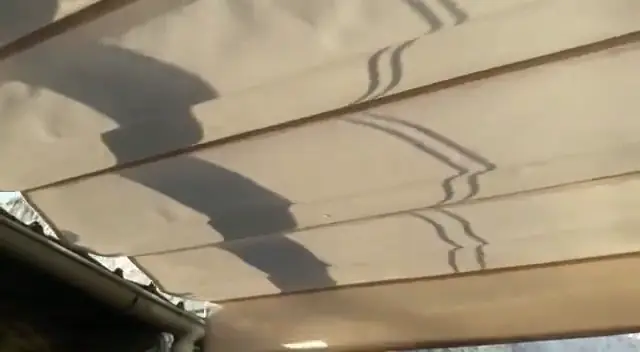 Toldo de lona en movimiento bajo una estructura de patio