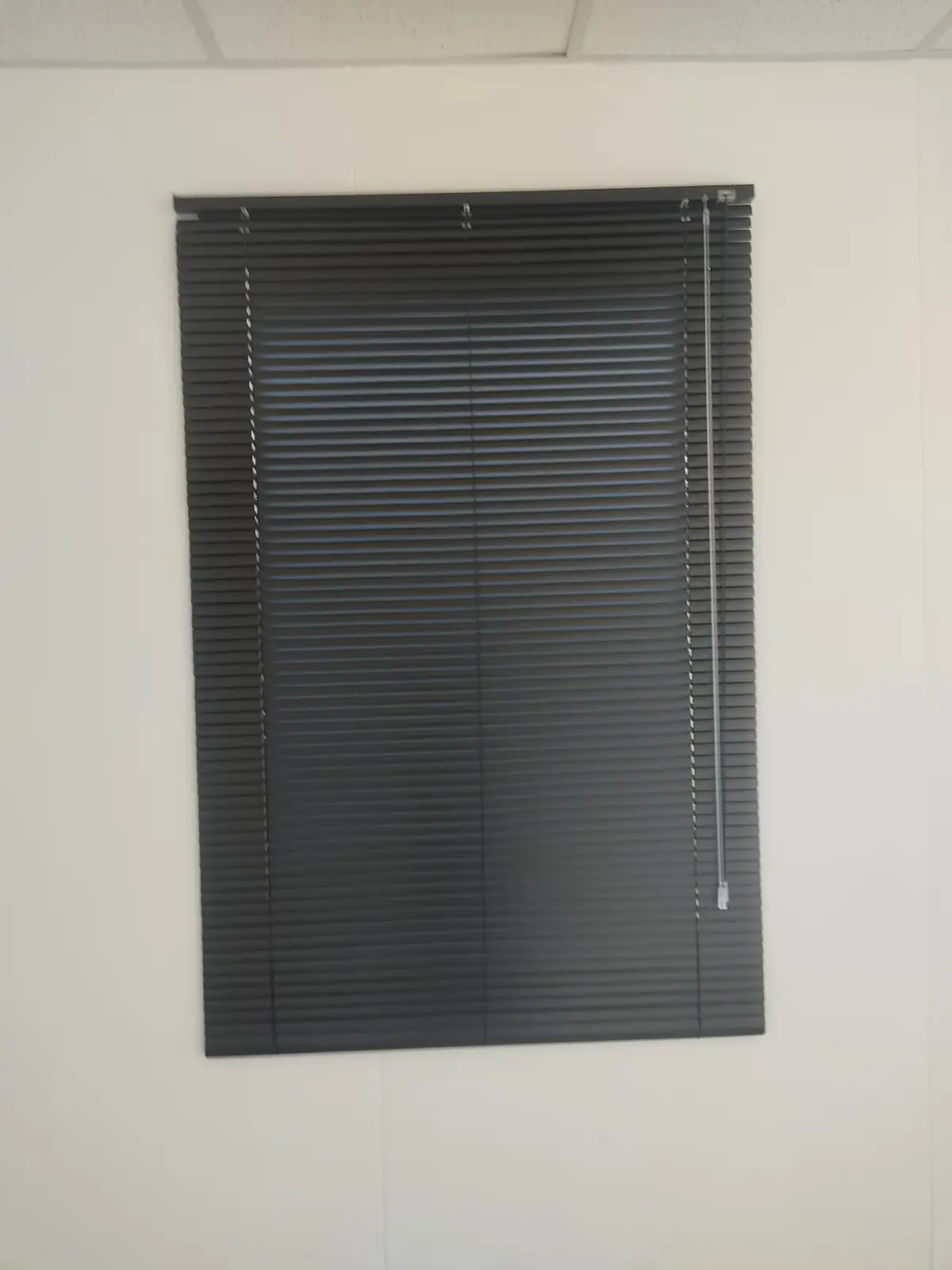 Cortina veneciana de aluminio negro cerrada sobre una ventana