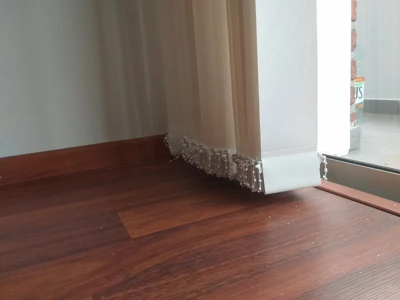Detalle de bandas verticales de tela abiertas junto a una ventana