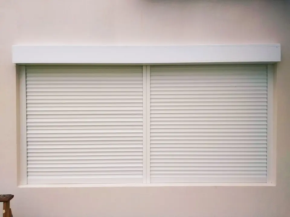 Cortina de enrollar blanca con cajón superior sobre una ventana